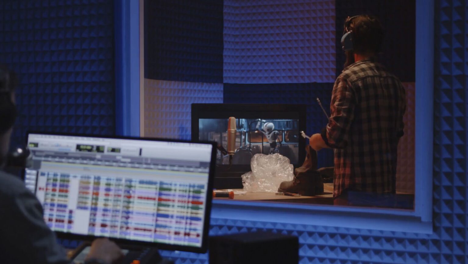 Foley artist working in recording studio while sound engineer observes