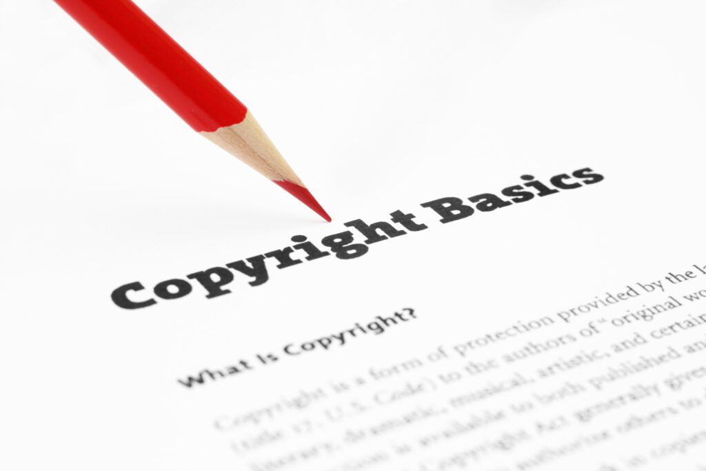 Image of a piece of paper that says copyright basics with a red pencil hovering over it.